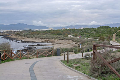 Footpath by railing against sky