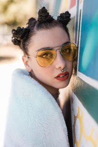 Close-up portrait of young woman standing by wall