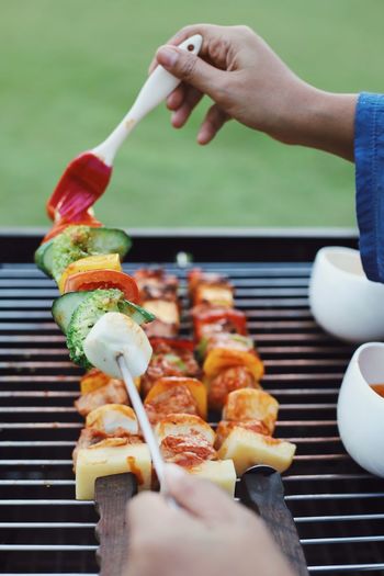 Close-up of person preparing food on barbecue grill