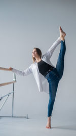 Full length of young woman exercising against white background