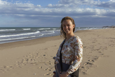 Young caucasian woman walking alone on the sandy beach at sunset