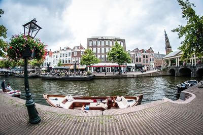 Boats in river by buildings in city against sky