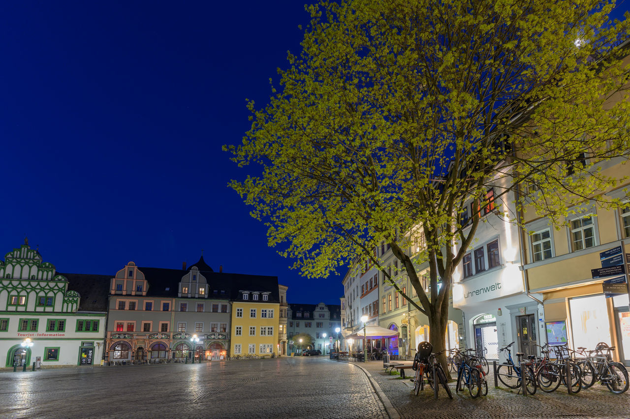 STREET AMIDST BUILDINGS AGAINST SKY AT NIGHT