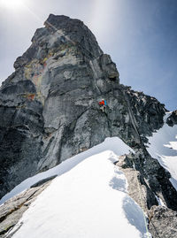 Male rock climbing giant peak in snow