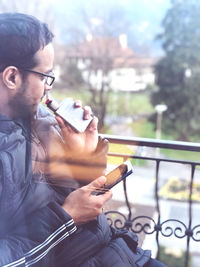 Man using mobile phone while smoking electronic cigarette