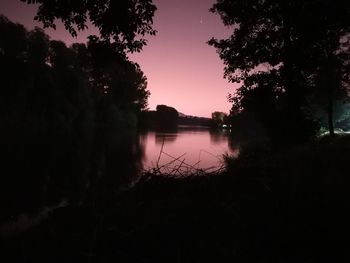 Silhouette trees by lake against sky during sunset