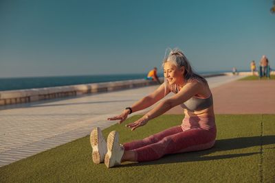 Side view of woman sitting on chair at beach