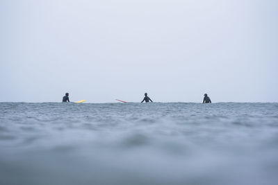 People on sea against clear sky