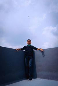 Full length portrait of young man standing against sky