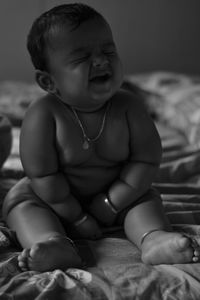 Cute baby boy sitting on bed