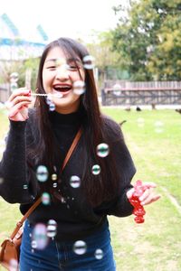 Cheerful teenage girl blowing bubbles outdoors