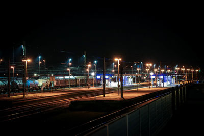 Illuminated railroad tracks against clear sky at night