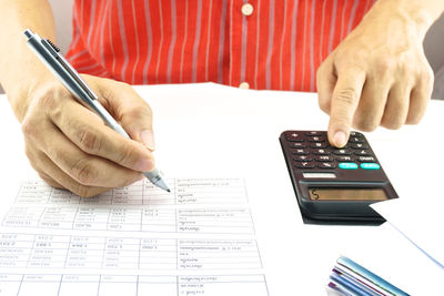 Midsection of man calculating bills on desk