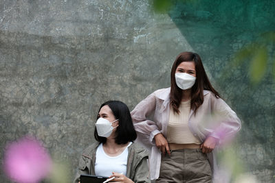 Portrait of young woman standing against wall