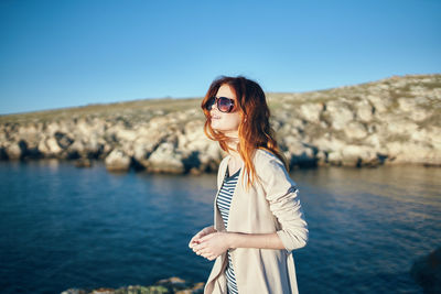 Man wearing sunglasses standing by sea against sky