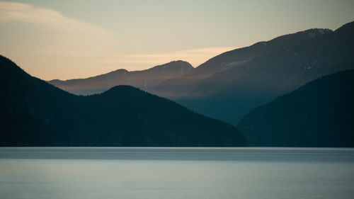 Scenic view of lake and mountains against sky during sunset