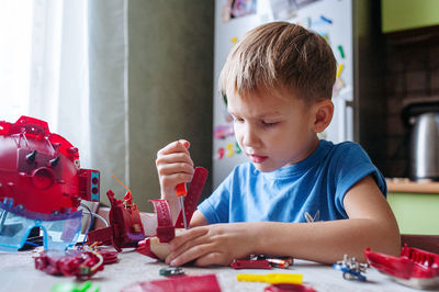 Boy takes apart toys with a screwdriver