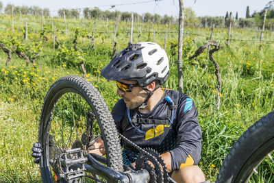 Young man repairing mountain bike on field