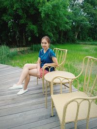 Portrait of young woman sitting on chair against plants