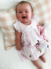 Directly above portrait of cute baby girl lying down on bed at home