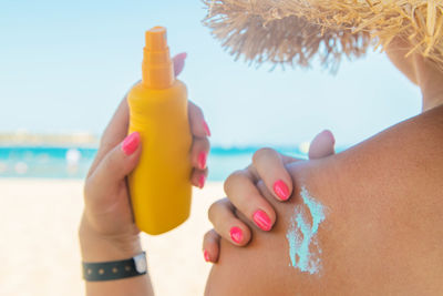 Midsection of woman hand holding bottle at beach