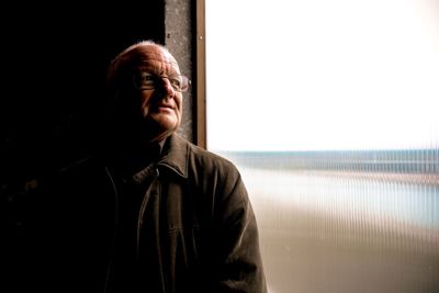 Thoughtful senior man looking through window