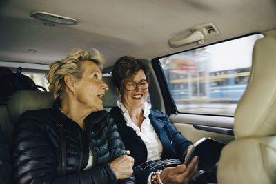 Senior woman talking with friend using mobile phone in car