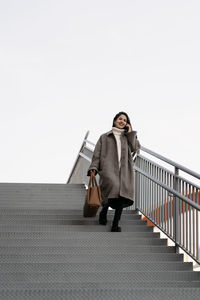 Low angle view of woman walking on staircase against sky