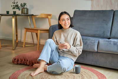 Young woman sitting on sofa at home