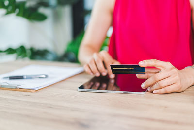 Midsection of woman using mobile phone on table