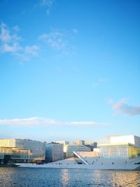 Buildings by sea against blue sky