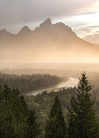 Scenic view of mountains against sky during sunset while raining with mist