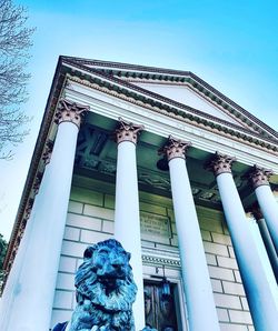 Low angle view of statue against building against blue sky