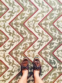 Low section of man standing on designed tiled floor