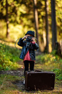 Cute girl photographing in forest