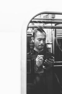Portrait of young man using mobile phone in mirror