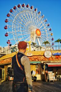 Rear view of man with ferris wheel in city