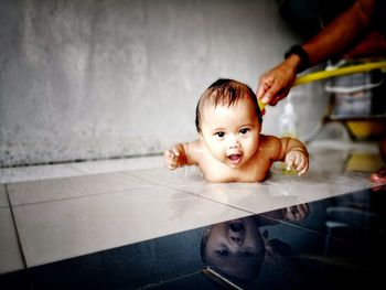 Portrait of cute baby boy having bath on floor