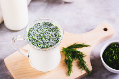 Glass with fresh turkish ayran with dill and greens on the table