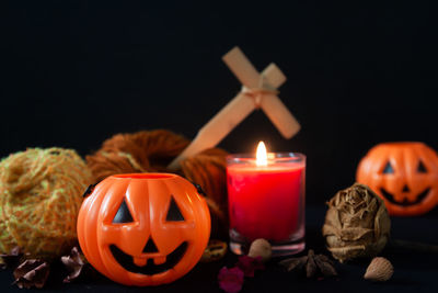 Lit candles on pumpkin against black background