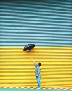 Full length of smiling girl against yellow wall