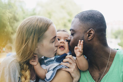 Close-up of multi-ethnic parents kissing son