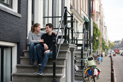 Young couple sitting on steps in city