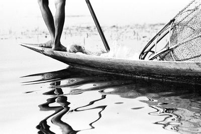 Low section of fisherman standing on boat in lake