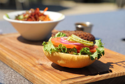 Close-up of burger and veggie on cutting board