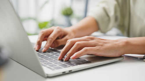 Midsection of woman using laptop at table