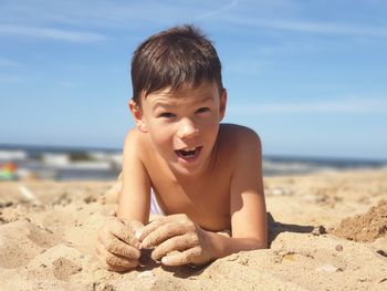 Boy on sand at beach against sky