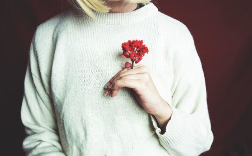 Midsection of woman holding red flowers
