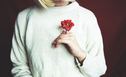 Midsection of woman holding red flower