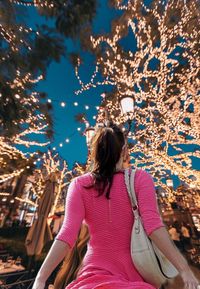 Rear view of woman with pink umbrella against trees